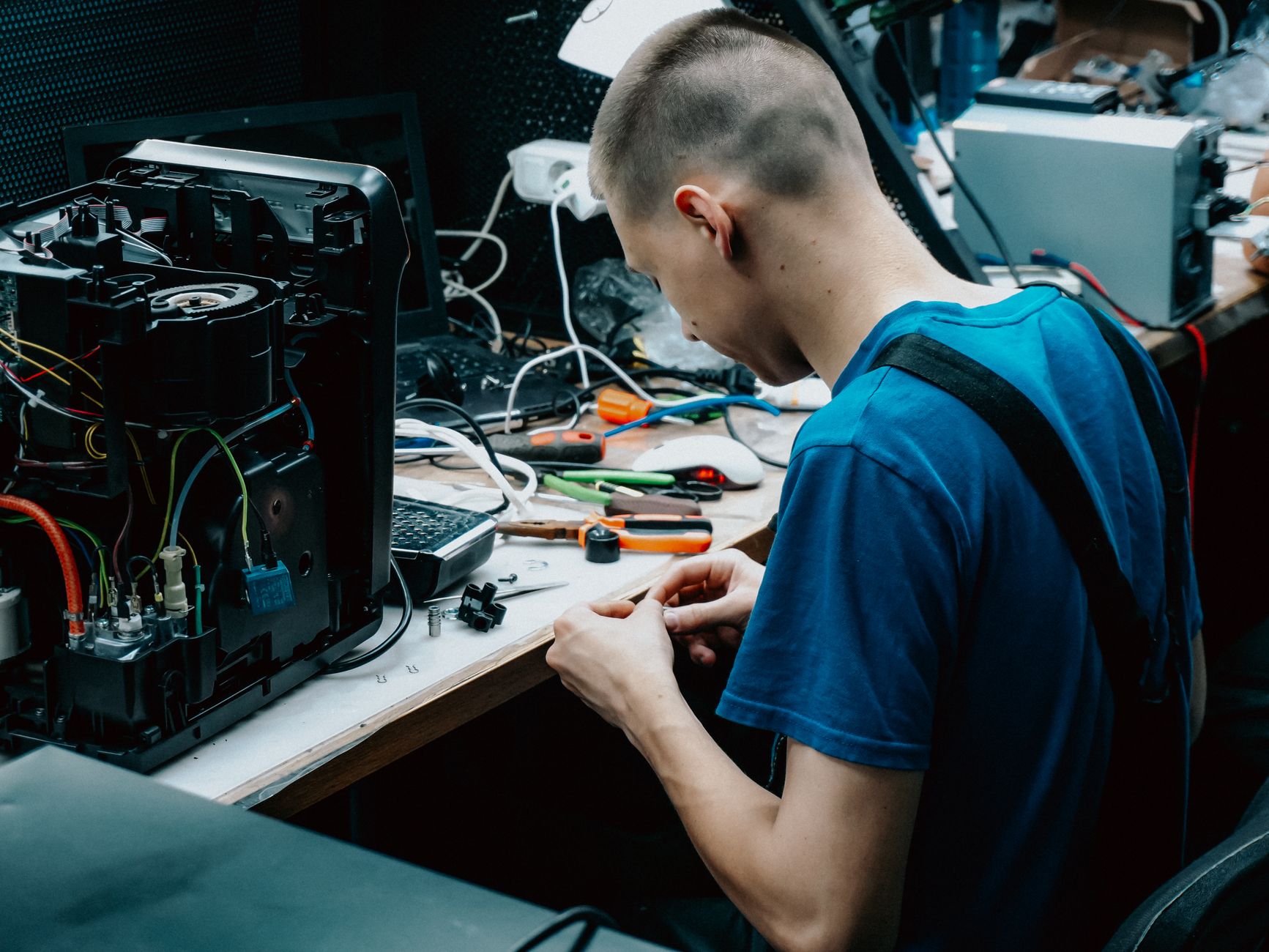 Technikus elektronikai eszközt javít a szerviz munkaasztalánál